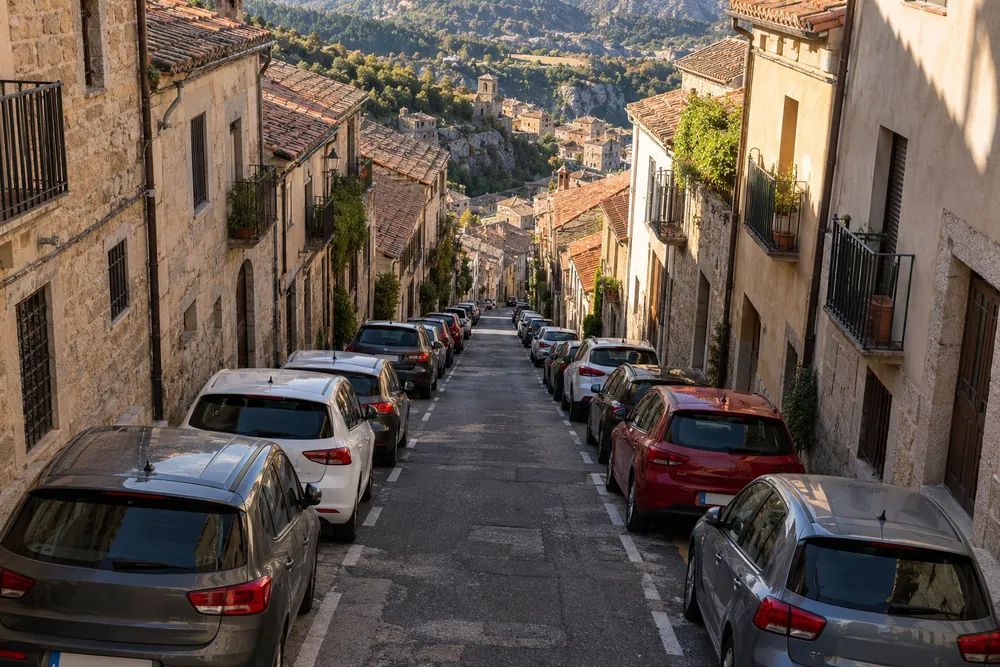 Calle urbana con una pendiente muy pronunciada y coches estacionados junto al bordillo.