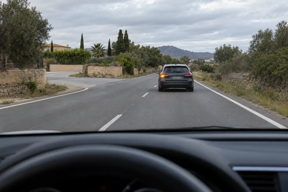 Turismo que se desplaza hacia el centro de la calzada con el intermitente izquierdo puesto, visto desde el coche de detrás.