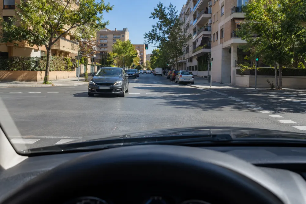 Turismo esperando en un cruce para girar a la izquierda mientras otro vehículo viene de frente y sigue recto.