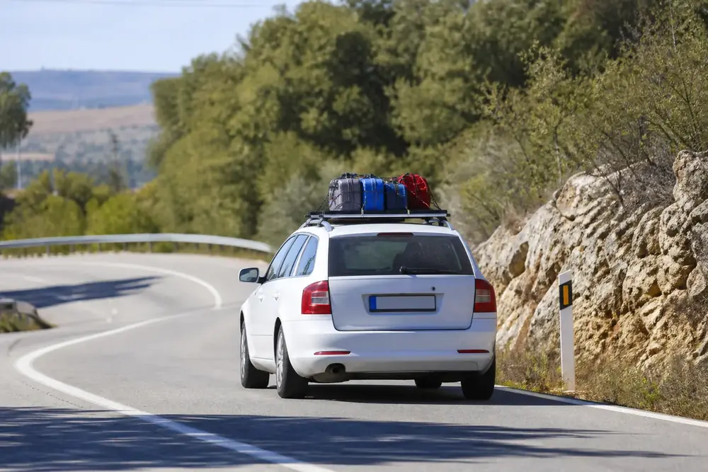 Coche con equipaje sujeto en la baca tomando una curva