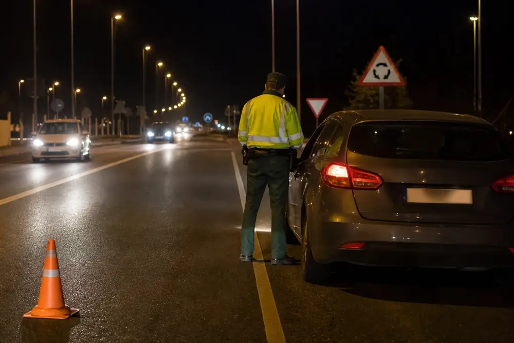Control nocturno con agente y cono junto a un vehículo detenido