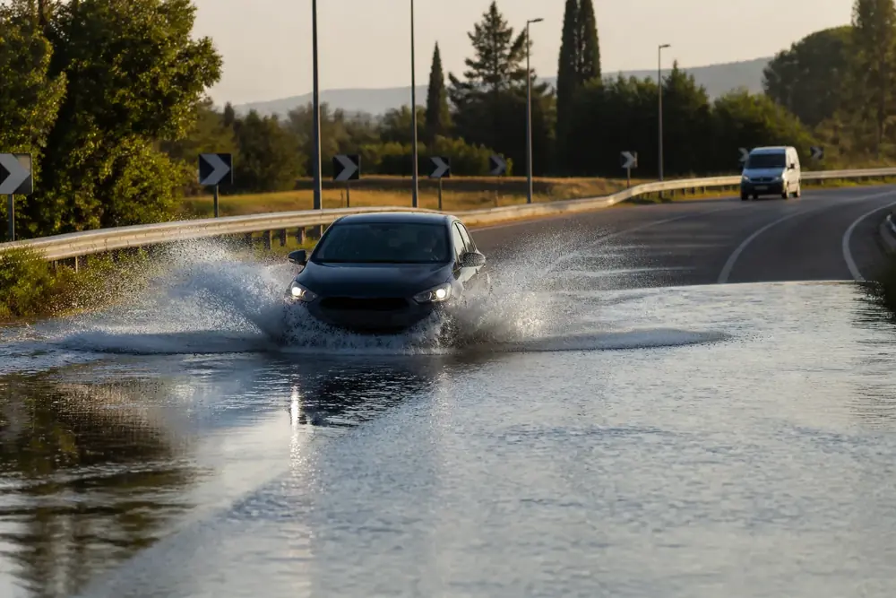 Turismo atravesando agua acumulada en la calzada al atardecer